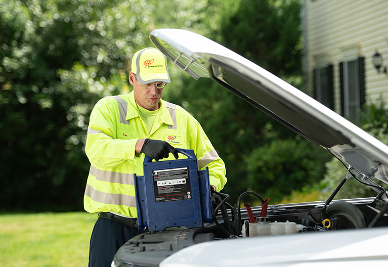 Battery service technician jump starting a vehicle. 