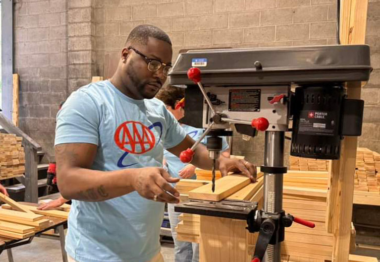 AAA employee doing woodwork at a volunteer event. 