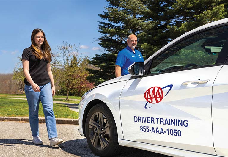 Driving instructor and student approach a driver training vehicle.