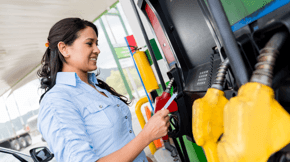 Woman smiling while pumping gas.