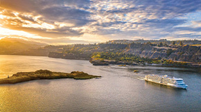 An American Cruise Lines ship traveling between an island and land.