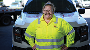 Automotive technician standing in front of their vehicle.