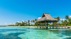 A covered dock along a tropical beach.