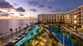 Aerial view of the Hilton Cancun Resort, including two pools during a sunset.