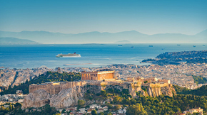 A faraway view of a cruise ship in the ocean next to a seaside mediterranean city