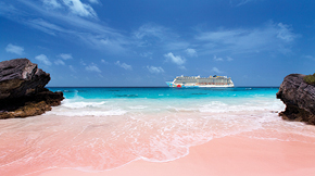 A white sand beach on a bright sunny day, with clear blue water and a norwegian cruise boat in the distance. 
