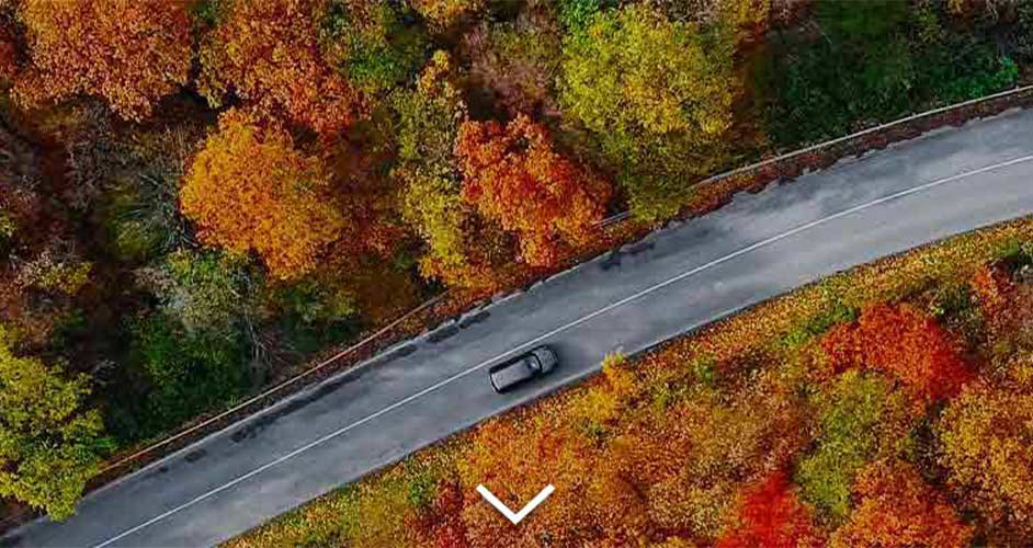 aerial view of a fall landscape and a car driving down the road