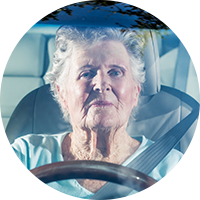 An elderly woman driving a car
