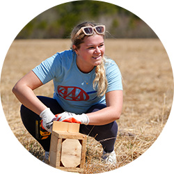 AAA employee crouched and smiling at a volunteer event.