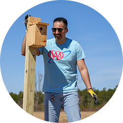 AAA employee standing next to a birdhouse.